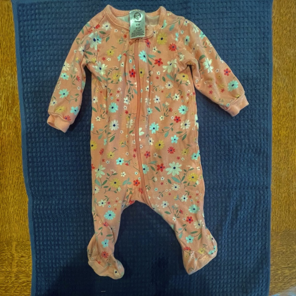 Cute baby girl onesie in trendy pink floral pattern.